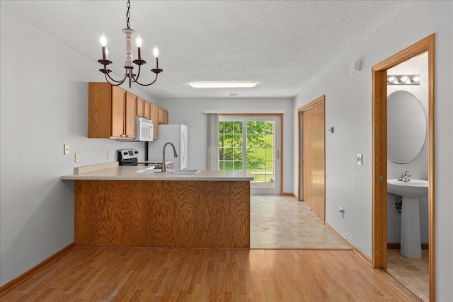 1960 Pika Trl Unit C, River Falls, WI 54022 - kitchen with white appliances, a peninsula, a chandelier, brown cabinets, and a textured ceiling