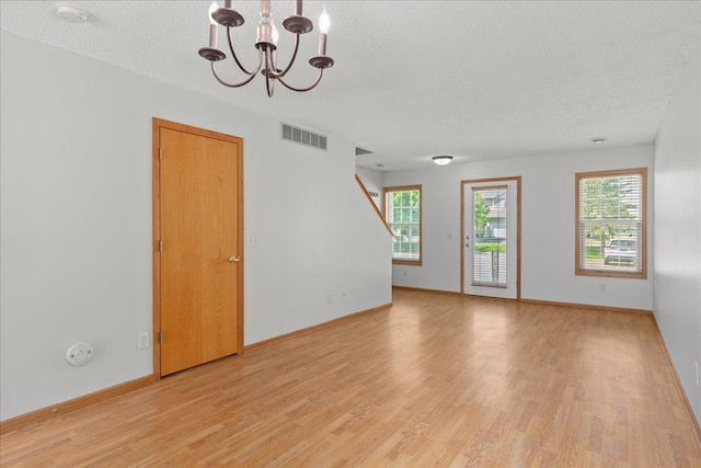 1960 Pika Trl Unit C, River Falls, WI 54022 - unfurnished living room with a chandelier, light wood-type flooring, a textured ceiling, and baseboards