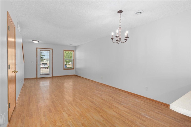 1960 Pika Trl Unit C, River Falls, WI 54022 - spare room with light wood finished floors, a chandelier, a textured ceiling, and baseboards