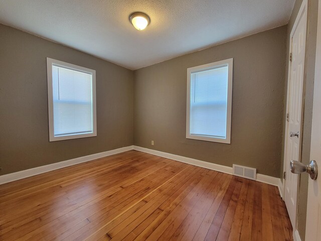 empty room featuring baseboards, light wood-type flooring, and visible vents