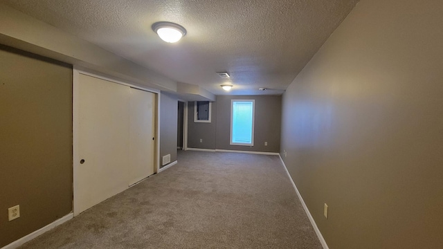 below grade area with carpet, baseboards, visible vents, and a textured ceiling