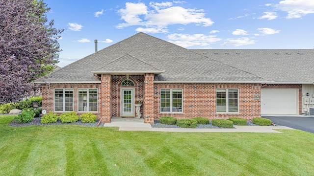 view of front of home with roof with shingles, an attached garage, brick siding, and a front yard
