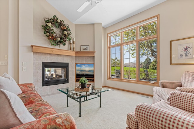 carpeted living room featuring a ceiling fan, baseboards, a tile fireplace, and lofted ceiling