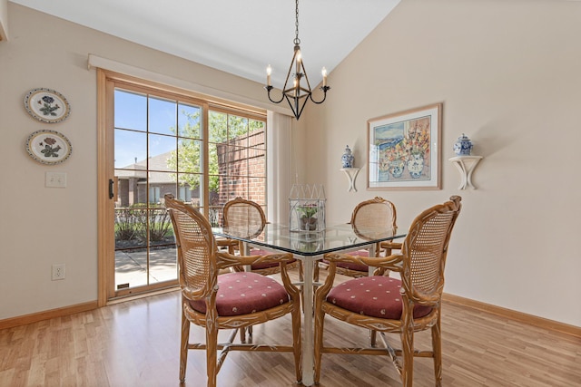 dining area featuring a chandelier, light wood-type flooring, vaulted ceiling, and baseboards