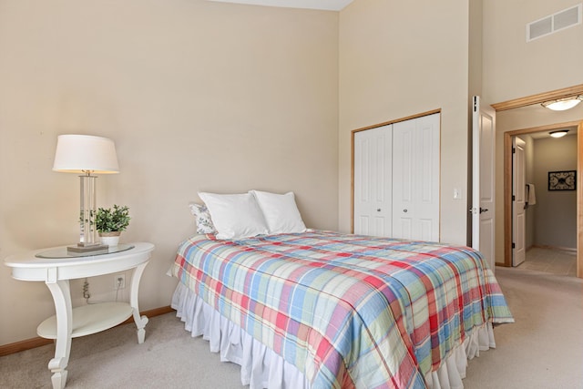 bedroom featuring light colored carpet, a towering ceiling, a closet, and baseboards