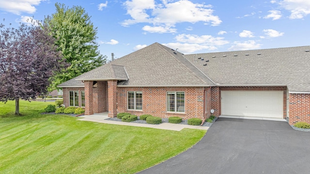 view of front of house featuring roof with shingles, brick siding, a garage, and a front yard