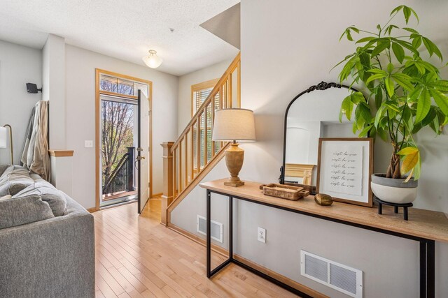 foyer entrance featuring a textured ceiling, visible vents, wood finished floors, and stairway