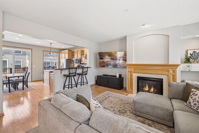 living room with light wood finished floors, recessed lighting, baseboards, and a glass covered fireplace