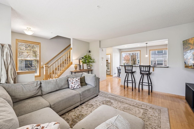 living area with stairs, hardwood / wood-style floors, and a healthy amount of sunlight