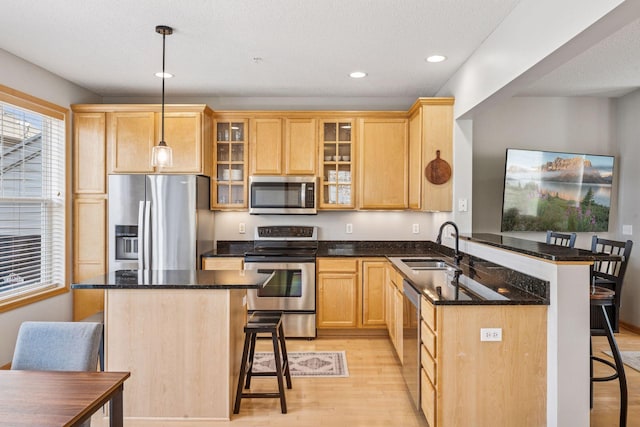 kitchen with light wood finished floors, stainless steel appliances, a sink, and a breakfast bar