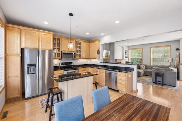 kitchen featuring stainless steel appliances, light wood-style flooring, a sink, and light brown cabinetry