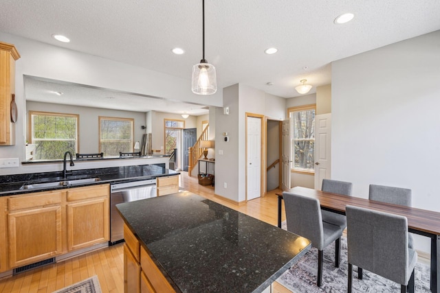 kitchen with light wood-style flooring, a textured ceiling, dishwasher, visible vents, and a sink