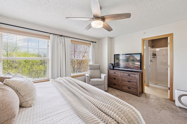 bedroom featuring ceiling fan, light carpet, a textured ceiling, and ensuite bath