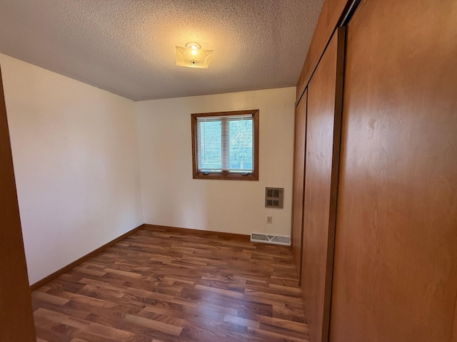 321 Western Ave, Madison, MN 56256 - unfurnished bedroom with wood finished floors, a closet, baseboards, a textured ceiling, and heating unit