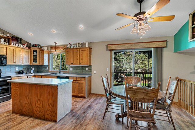 kitchen with black microwave, double oven range, light countertops, decorative backsplash, and light wood-style floors