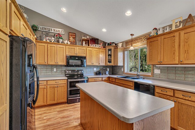 kitchen featuring black appliances, a sink, lofted ceiling, light wood-style flooring, and backsplash