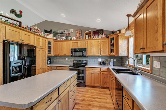 kitchen featuring black appliances, a sink, lofted ceiling, light wood finished floors, and light countertops