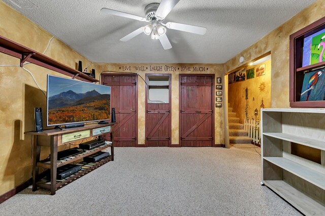 living room with a ceiling fan, carpet, a textured ceiling, and stairs