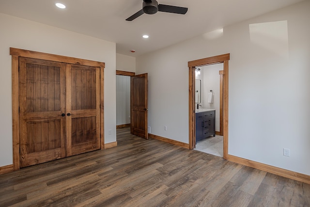 unfurnished bedroom featuring wood finished floors, baseboards, recessed lighting, ensuite bath, and ceiling fan