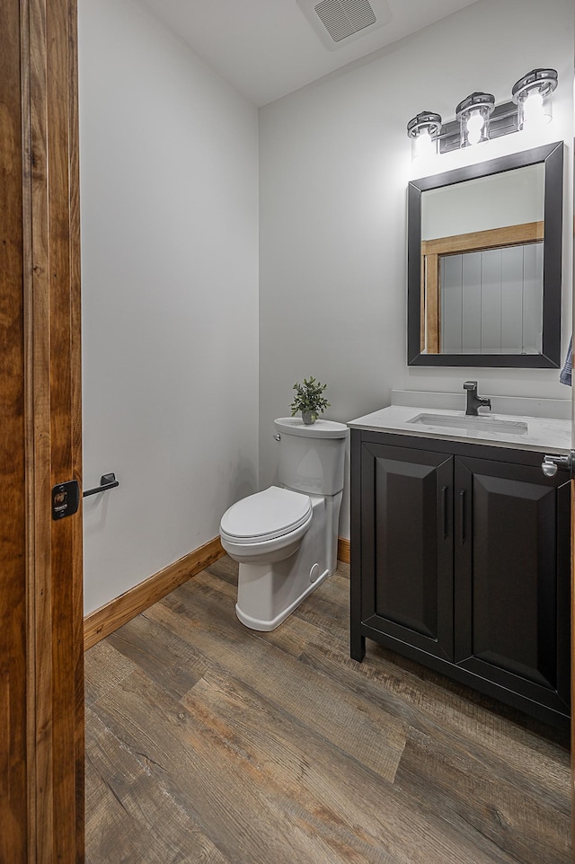 bathroom with wood finished floors, toilet, and vanity