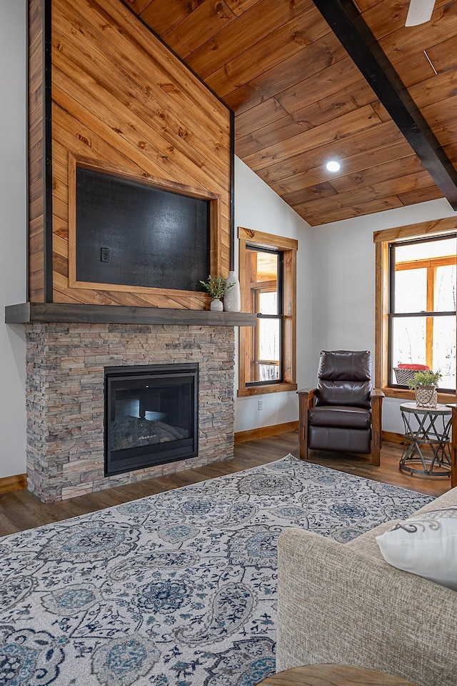 living area featuring wood ceiling, baseboards, wood finished floors, and a stone fireplace