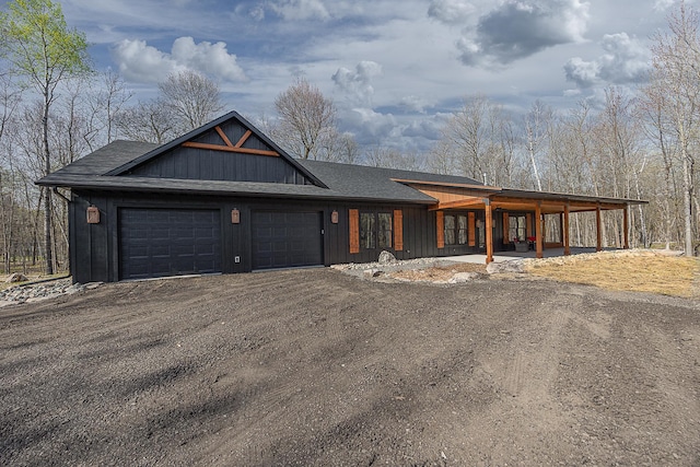 view of front facade featuring a garage, driveway, covered porch, roof with shingles, and board and batten siding