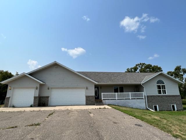 single story home featuring brick siding, covered porch, a garage, and aphalt driveway