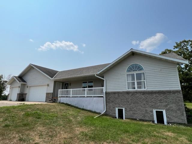 single story home featuring covered porch, a front yard, brick siding, and a garage
