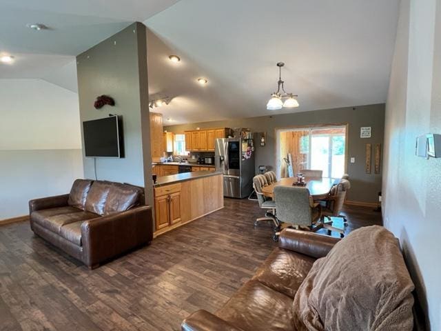 living area with an inviting chandelier, dark wood-type flooring, baseboards, and lofted ceiling