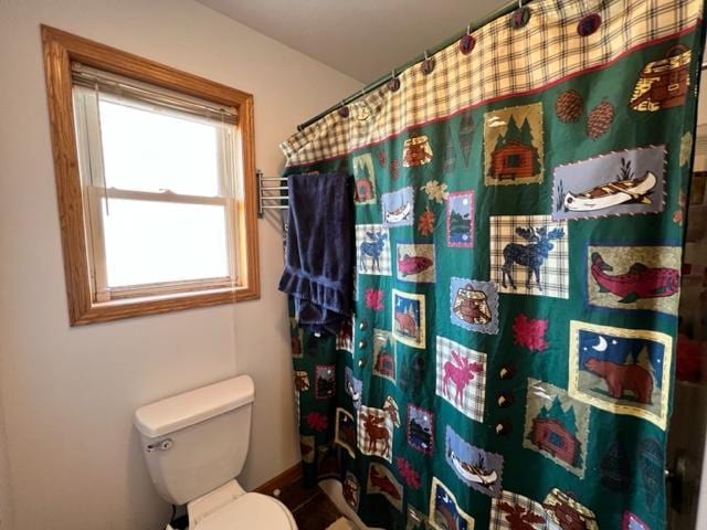 bathroom with toilet, a shower with shower curtain, and baseboards