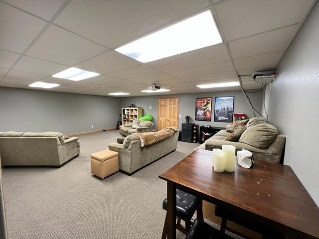 living area with a paneled ceiling and carpet floors