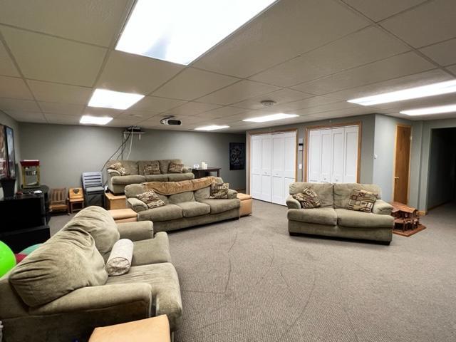 living area with carpet and a paneled ceiling