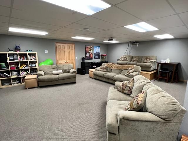 living area featuring carpet and a drop ceiling