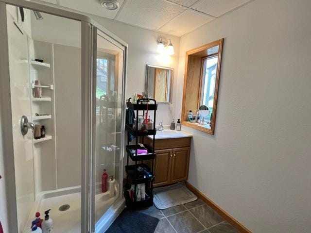 full bath featuring vanity, tile patterned floors, a stall shower, a paneled ceiling, and baseboards