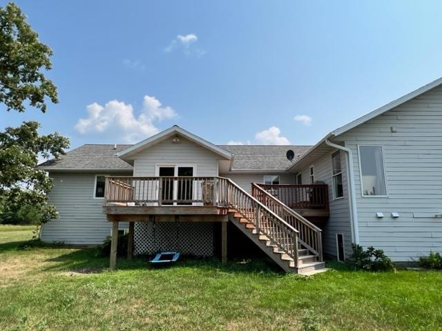 rear view of house featuring a lawn, a wooden deck, and stairs