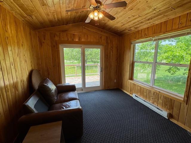 18851 121st Ave, Leaf River Twp, MN 56482 - living area with baseboard heating, wood walls, lofted ceiling, ceiling fan, and healthy amount of natural light
