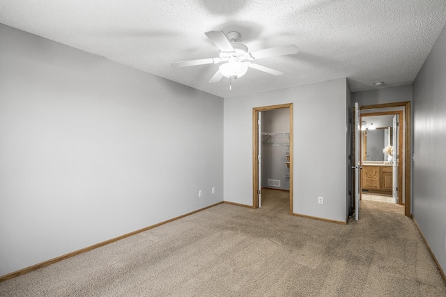 7327 Kalland Cir NE Unit 28, Otsego, MN 55301 - unfurnished bedroom with a walk in closet, carpet, a closet, baseboards, and ceiling fan