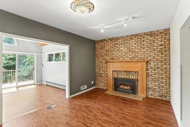 5820 139th St W, Apple Valley, MN 55124 - unfurnished living room featuring baseboard heating, wood finished floors, a brick fireplace, and track lighting