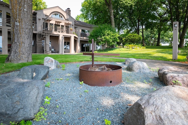 9002 Riley Lake Rd, Eden Prairie, MN 55347 - back of house featuring a chimney, a lawn, stairway, an outdoor fire pit, and stucco siding
