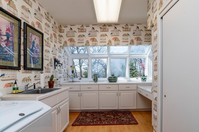 9002 Riley Lake Rd, Eden Prairie, MN 55347 - kitchen featuring a sink, light wood-style flooring, white cabinetry, washer / dryer, and light countertops