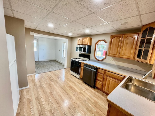 125 1st St, Dresser, WI 54009 - kitchen featuring white appliances, light wood-style floors, a paneled ceiling, a sink, and light countertops