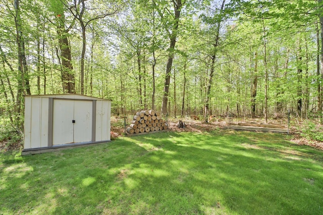 view of green lawn featuring a storage unit, an outdoor structure, and a view of trees