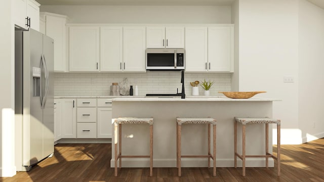 kitchen featuring appliances with stainless steel finishes, dark wood-style flooring, a breakfast bar area, light countertops, and decorative backsplash