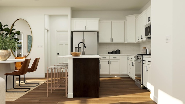 kitchen featuring stainless steel appliances, decorative backsplash, dark wood-type flooring, light countertops, and a center island with sink