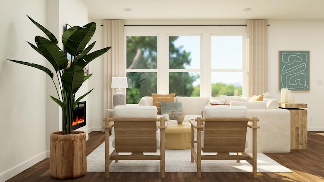 living area with healthy amount of natural light, a lit fireplace, and wood finished floors