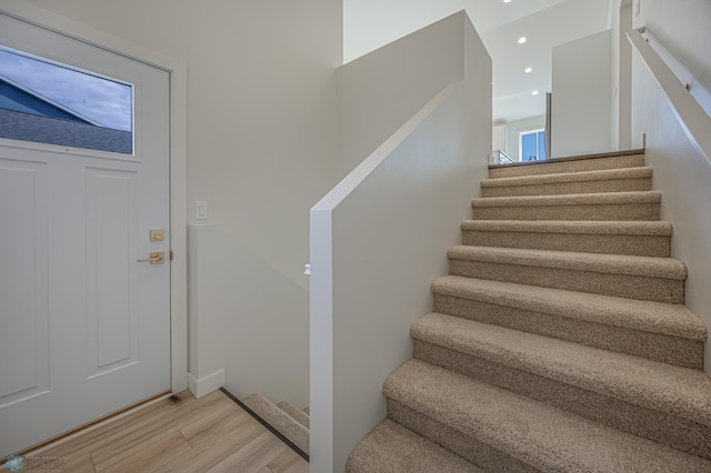 staircase with wood finished floors and recessed lighting