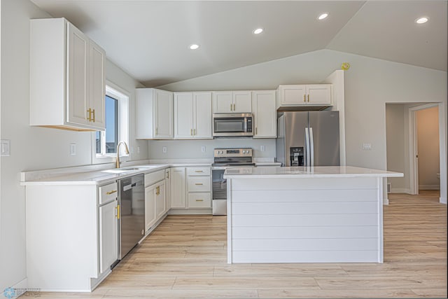 kitchen featuring appliances with stainless steel finishes, a sink, lofted ceiling, light countertops, and a kitchen island