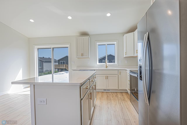 kitchen featuring stainless steel fridge, a sink, healthy amount of natural light, a center island, and recessed lighting