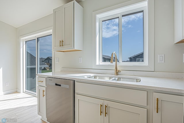 kitchen featuring dishwasher, a sink, light stone countertops, and white cabinets