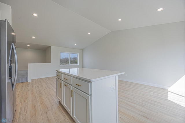 kitchen featuring stainless steel refrigerator with ice dispenser, light wood-style flooring, light countertops, a kitchen island, and recessed lighting